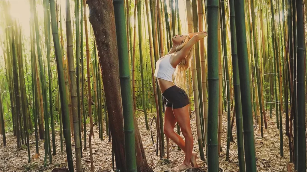 Odette stretching in a bamboo forest wearing a bamboo outfit