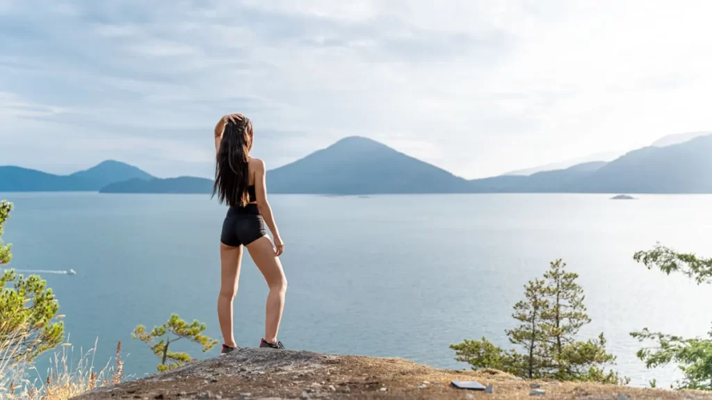 A women enjoying a beautiful ocean view wearing black shorts and sport bra 